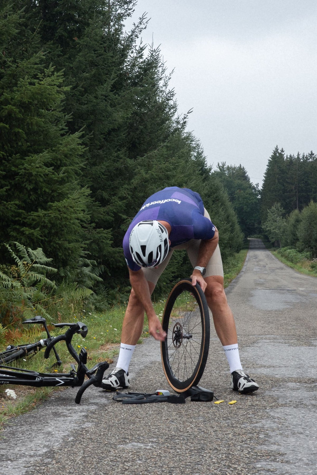 Cyclist fixing a flat tire on a gravel road